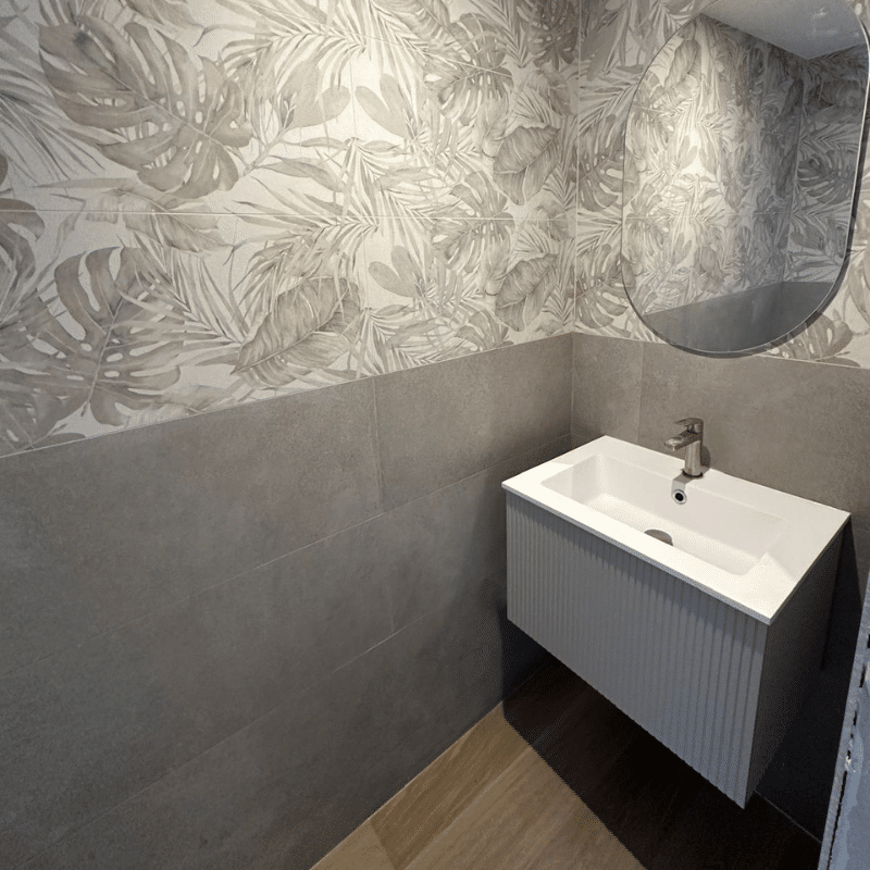 un lavabo dans une petite pièce avec un carrelage mural fleuri