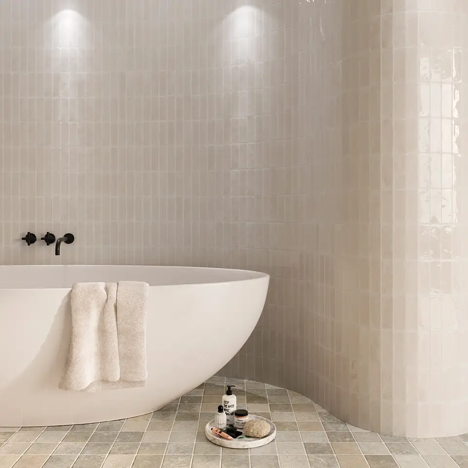 une salle de bain avec une baignoire et un carrelage clair wow au sol et au mur